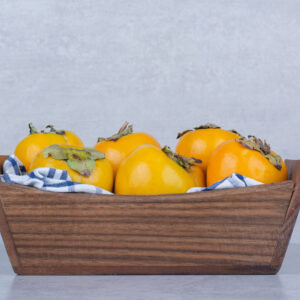 A wooden basket full of sweet persimmons on white background. High quality photo